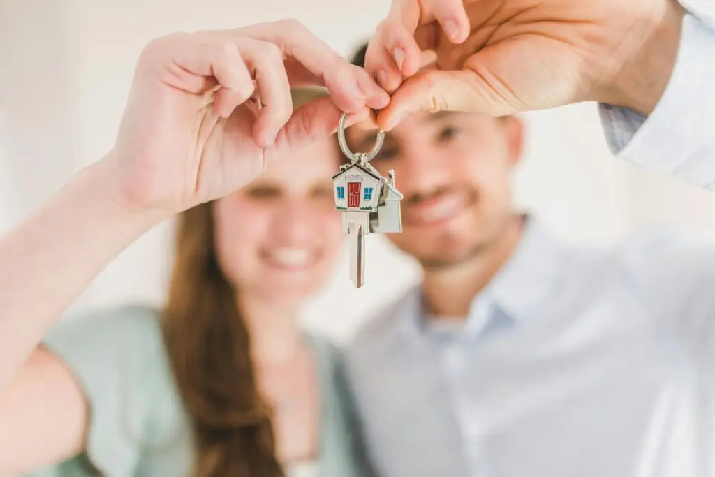 Happy couple holding keys in front of their new home